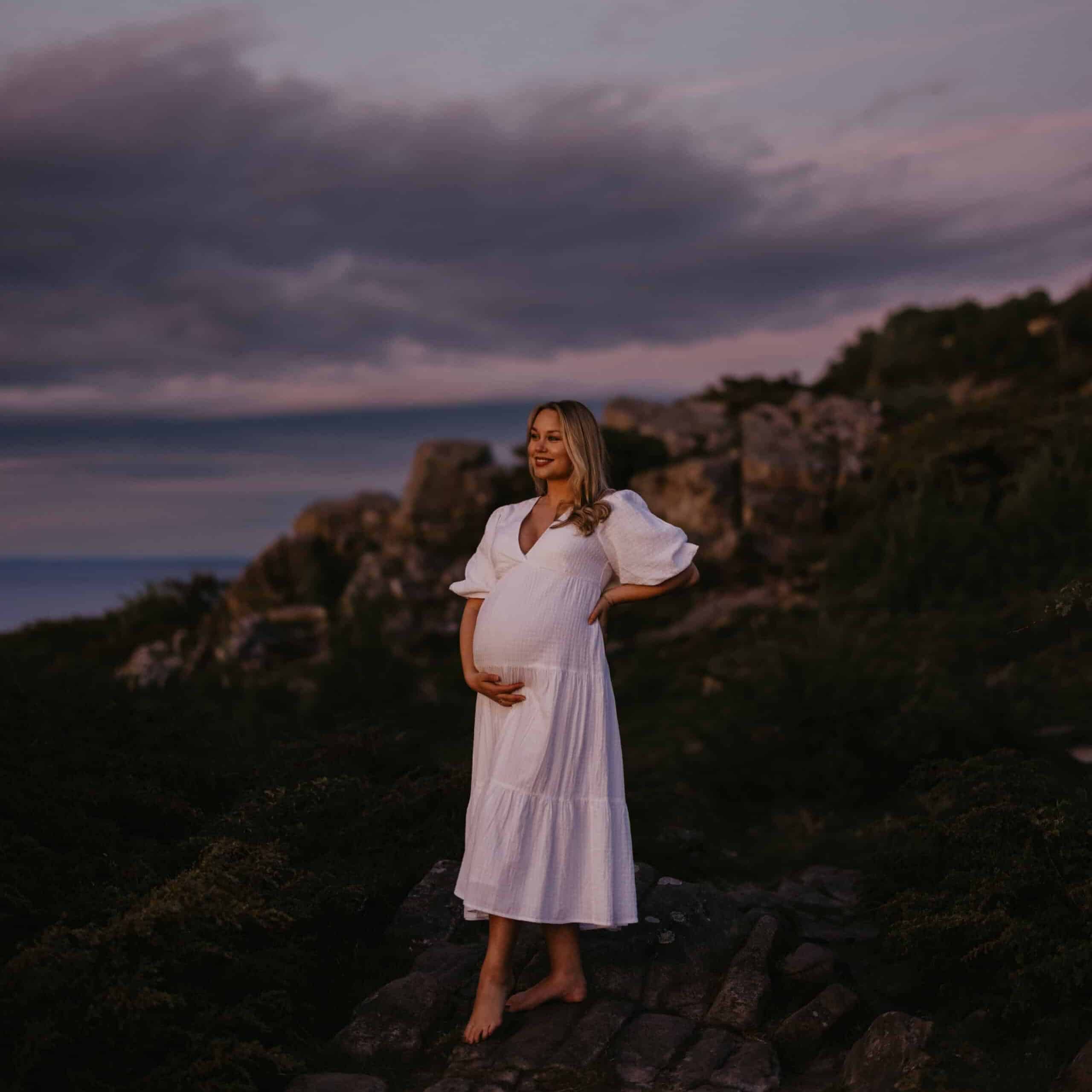 Vacker gravidfotografering i Skåne – kvinna poserar bland klippor Hovshallar